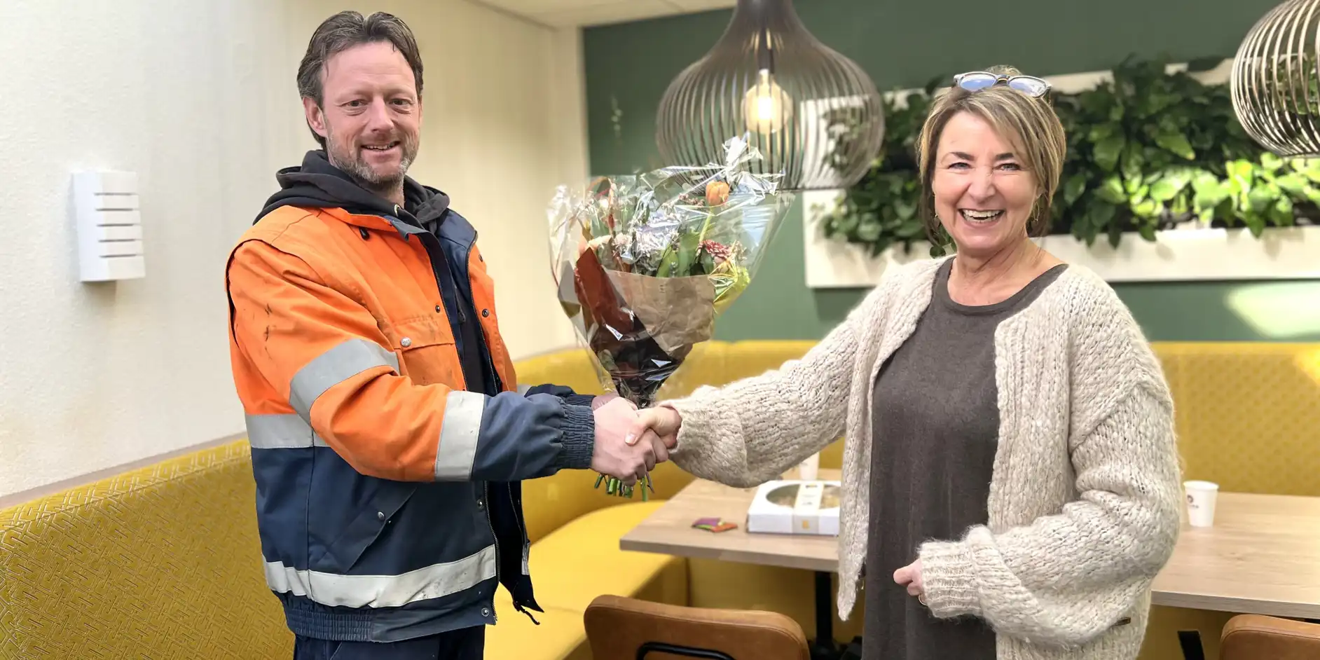Anna overhandigt Rob een bos bloemen op zijn nominatie te vieren.
